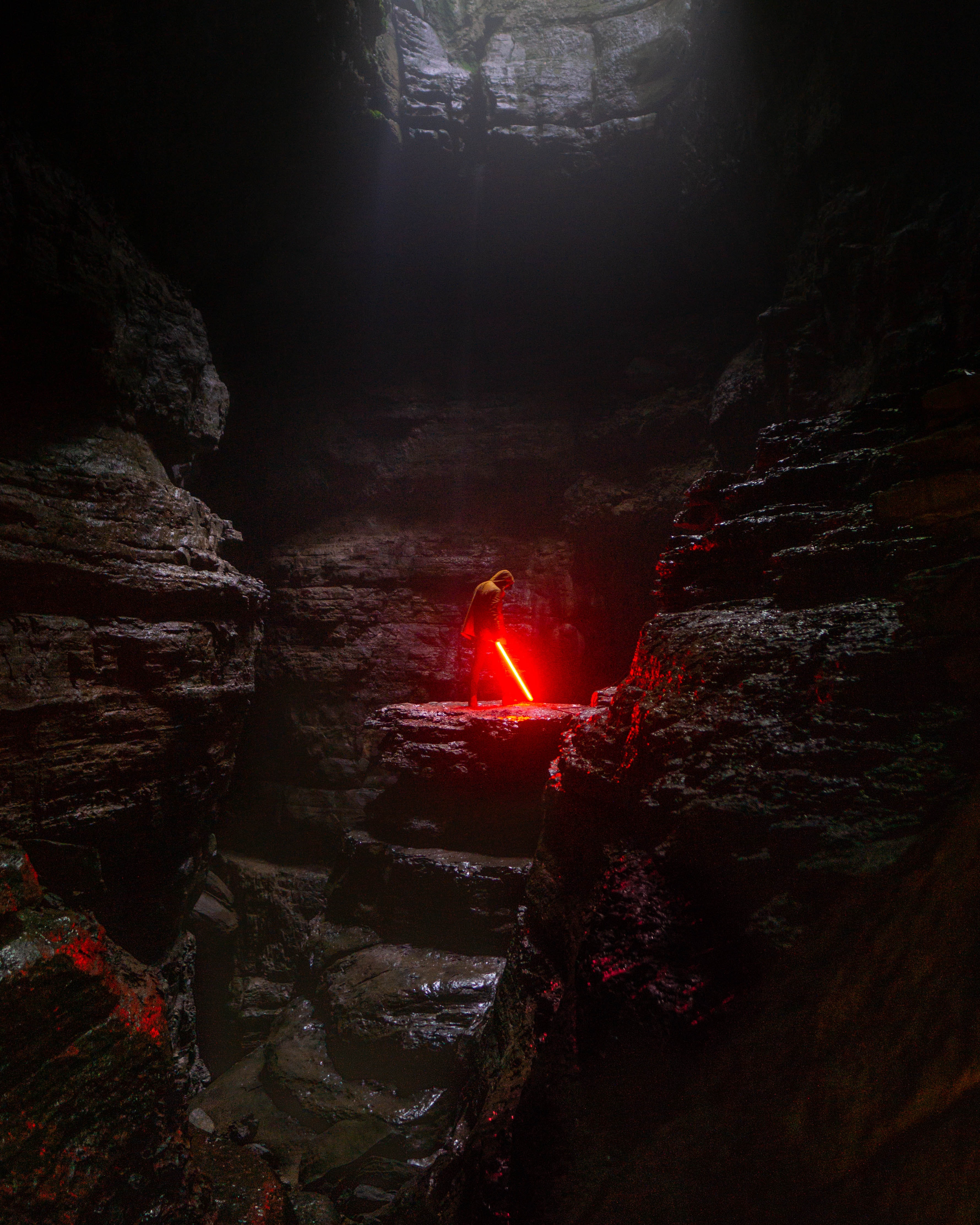 man holding red lightsaber in cave